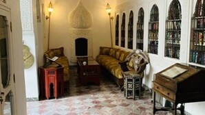 A room with a patterned floor, a sofa, a small table, a bookshelf, and a decorative lamp. - Riad Ifoulki (Marrakech)