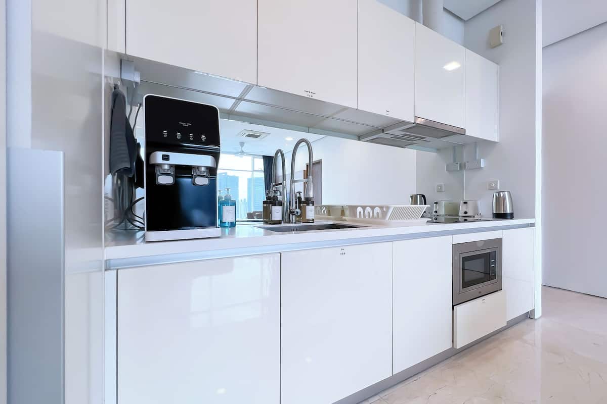 A modern kitchen with white cabinetry, a built-in coffee maker, a microwave, and a stainless steel sink.