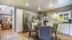 Una cocina moderna con armarios blancos, una isla central y una zona de comedor con dos sillas.