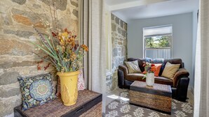 Una sala de estar acogedora con una pared de piedra, un sofá de cuero marrón y una mesa de centro con un jarrón de flores.