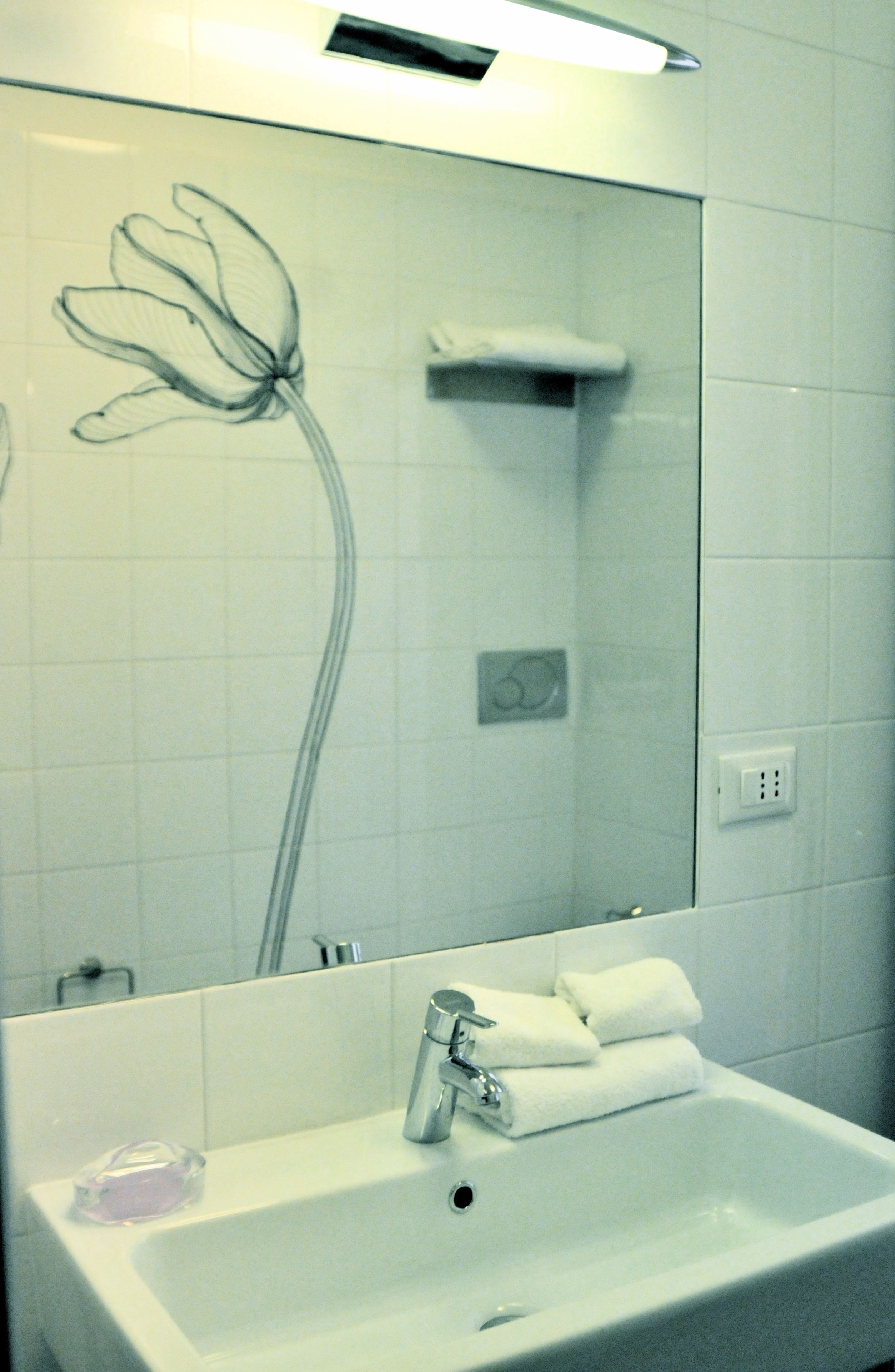 A bathroom with a white sink, a mirror, and a shower.