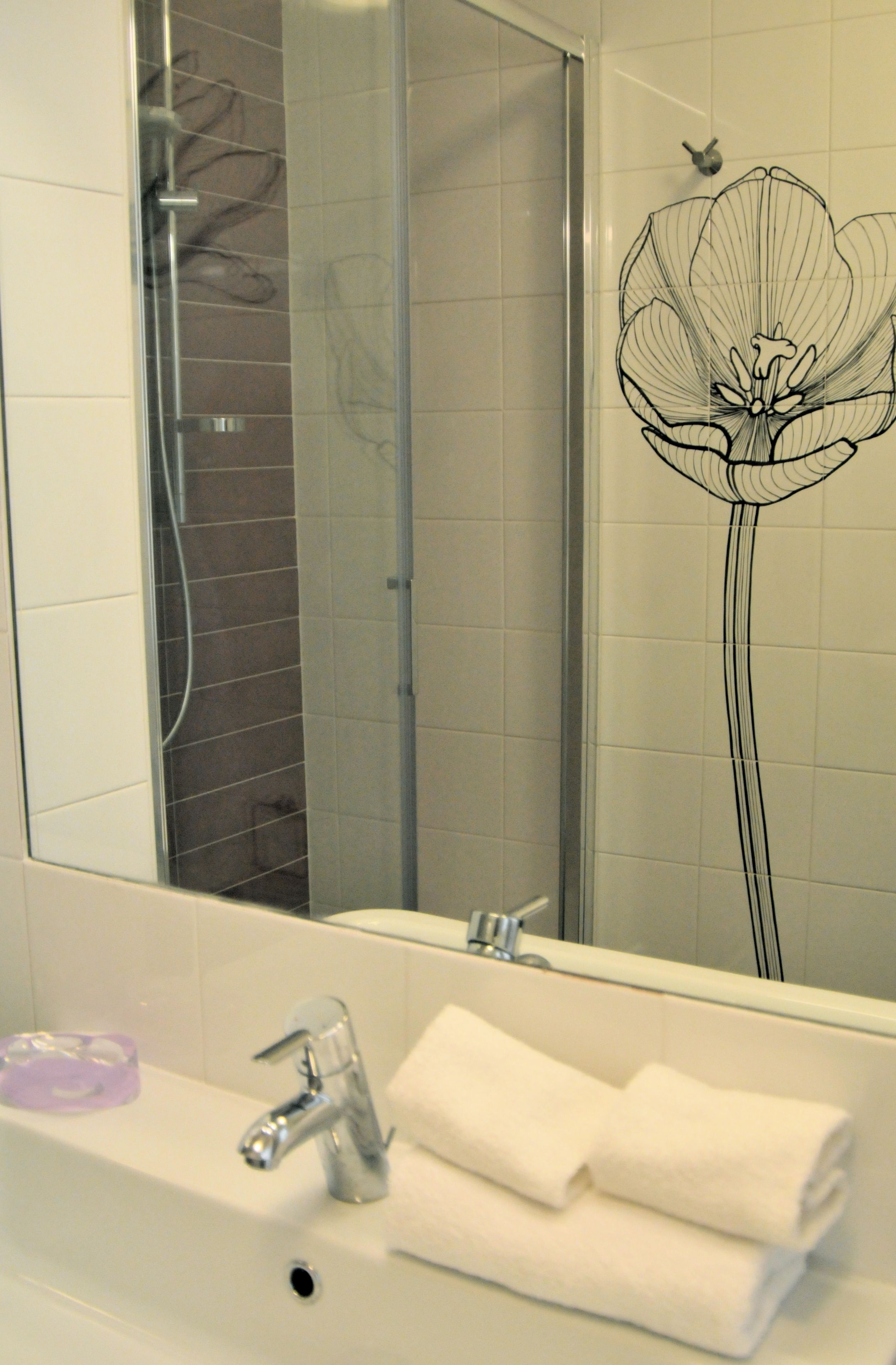 A bathroom with a white sink, a mirror, and a shower.