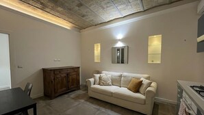 Una sala de estar con un sofá color beige, un mueble de madera y una mesa de comedor.
