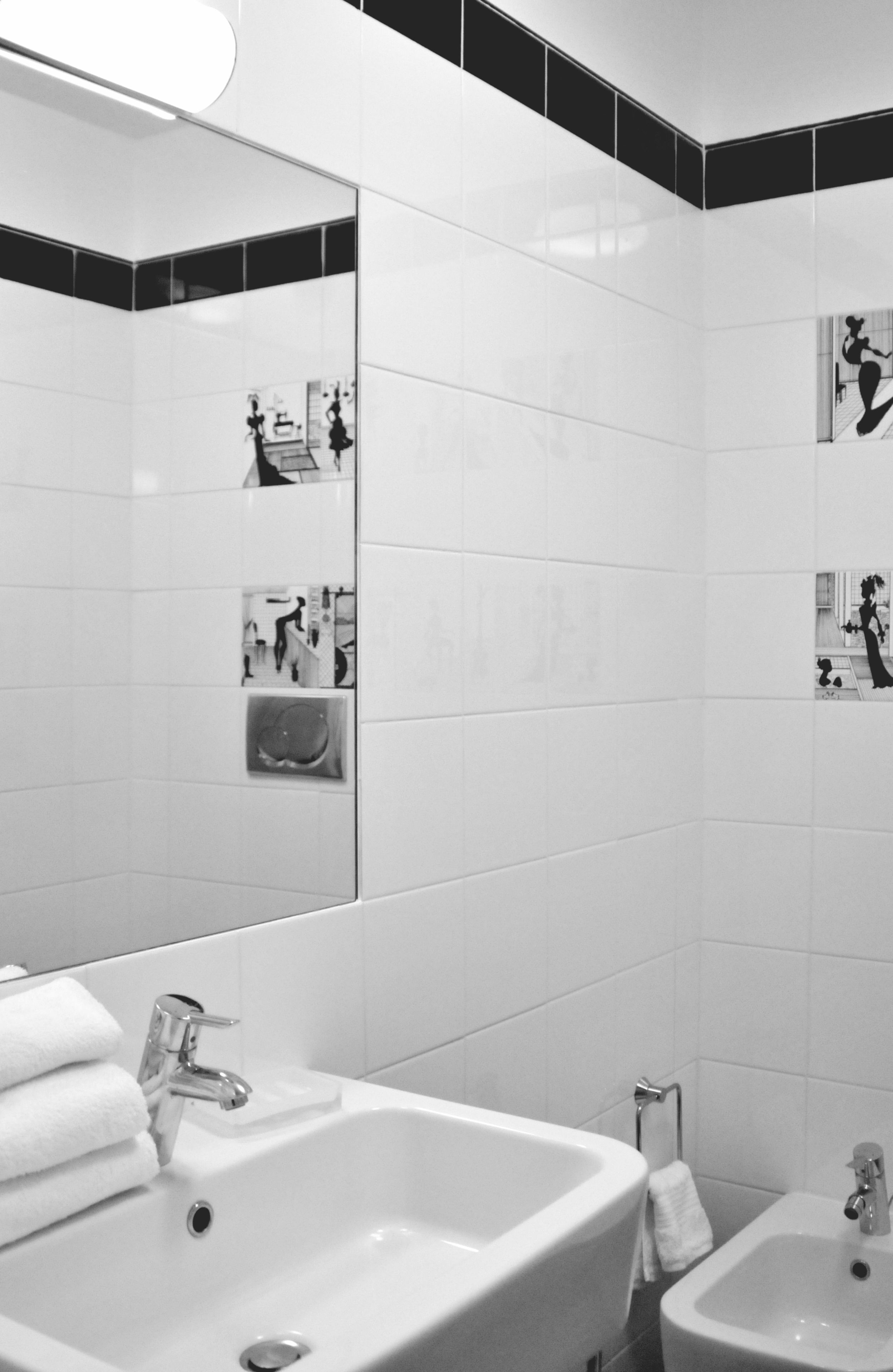 Un baño moderno con un espejo grande, dos lavamanos y un bidé pequeño.