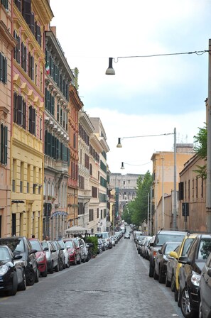 Una calle empedrada flanqueada por vehículos estacionados y edificios históricos.
