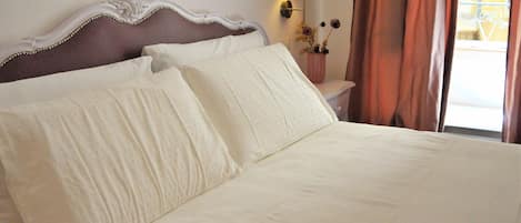 Una cama bien hecha con ropa blanca y un cabecero decorativo.