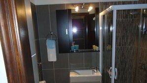 Un baño moderno con cabina de ducha de vidrio, un lavamanos y un espejo encima.