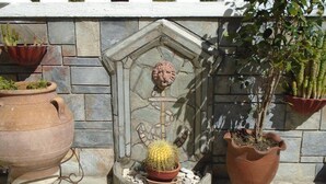 Un muro de piedra con un nicho decorativo que contiene un cactus y una escultura de cabeza de león.
