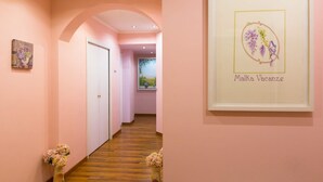 Un pasillo con paredes rosas, piso de madera y cuadros en la pared.