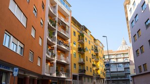 Un edificio de varios pisos con balcones, una estructura en forma de cúpula al fondo y un cielo despejado.