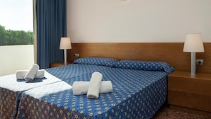 Een hotelkamer met een bed, twee nachtkastjes, een raam met gordijnen en een wandlamp.