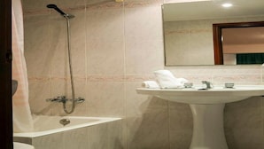 Een badkamer met een bad, douche en wastafel.