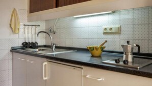 Een keuken met een dubbele spoelbak, een fornuis en een gele kom op het aanrecht.