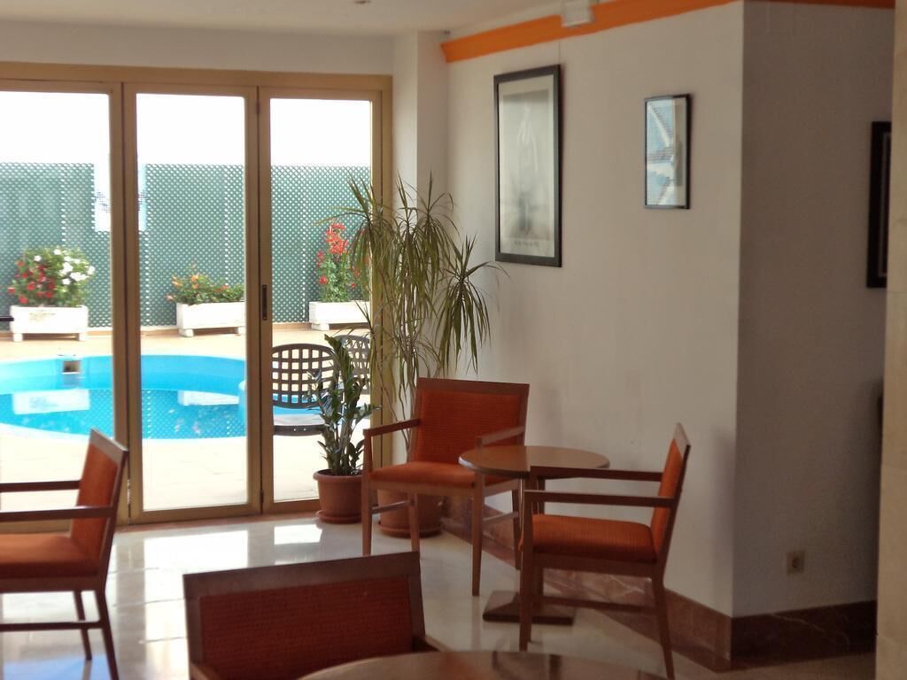 A room with a sliding glass door leading to a pool area, a potted plant, and a framed picture on the wall.