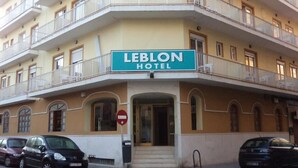 A hotel named 'LEBLON HOTEL' with a multi-story structure, balconies, and a signboard.