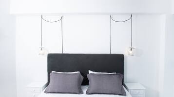 A modern bedroom with a black headboard, two bedside tables, and a white nightstand.