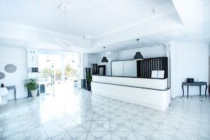 A modern reception area with a white reception desk, pendant lighting, and a view of the outside.