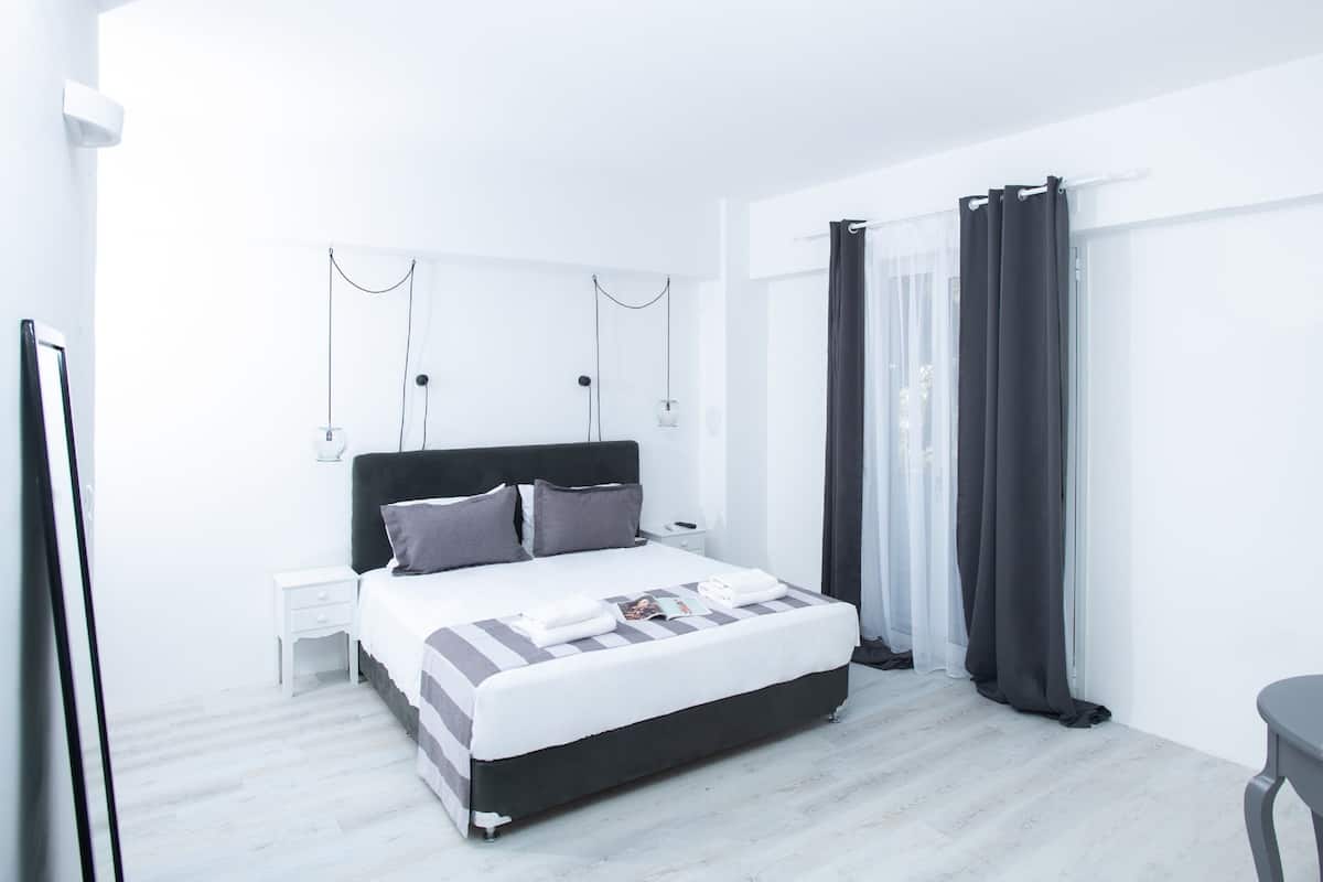 A modern bedroom with a large bed, bedside tables, and a window with curtains.