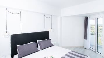 Una habitación de hotel moderna con una cama grande, una mesita de noche, una lámpara y vistas al exterior.