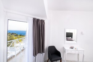 Quarto com varanda, uma cadeira, escrivaninha e espelho.