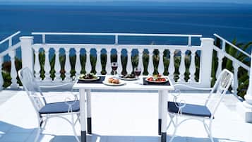 Een tafel voor twee, gedekt met eten en wijnglazen, met uitzicht op de kust.