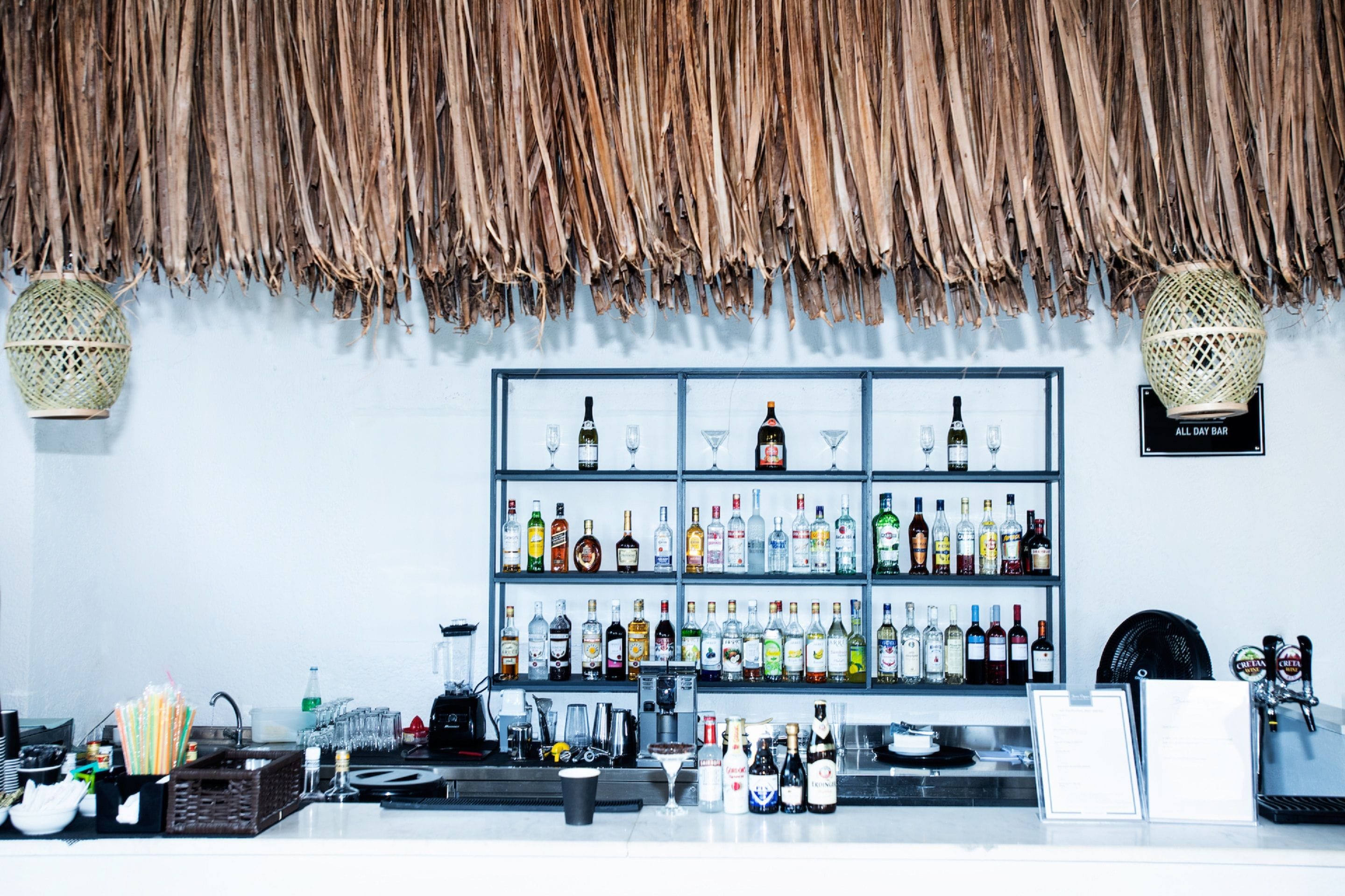 A bar area with shelves of various liquor bottles and glasses, a cash register, and a menu board.