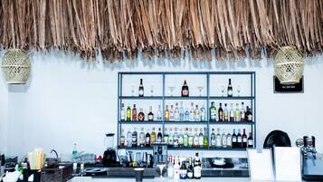 A bar area with shelves of various liquor bottles and glasses, a cash register, and a menu board.
