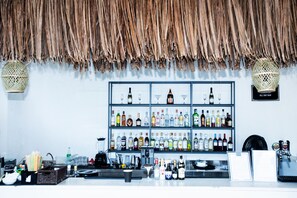 A bar area with shelves of various liquor bottles and glasses, a cash register, and a menu board.
