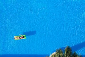 A clear blue swimming pool with a person floating on a green inflatable raft.