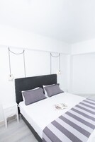 Quarto minimalista com uma cama grande, duas mesas de cabeceira e um lustre.