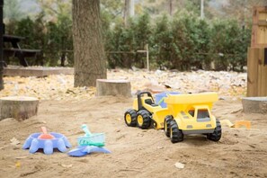 A sandbox with toy vehicles and a shovel.