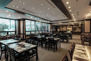 A restaurant with multiple tables and chairs, large windows, and a kitchen area. - Kensington Resort Gapyeong (Gapyeong-gun)