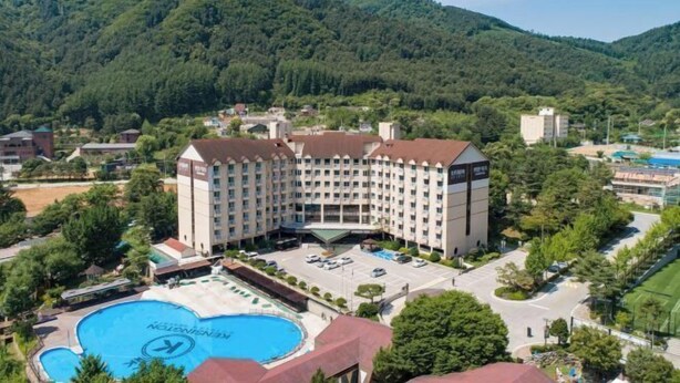 Un hotel con una piscina grande, rodeado de exuberante vegetación y montañas.