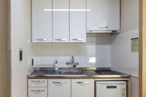 Una cocina compacta con gabinetes blancos, encimeras de acero inoxidable, lavavajillas integrado y un lavamanos doble.
