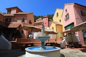 Un patio con fuente, mesas al aire libre y edificios coloridos.
