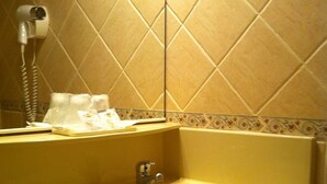 A bathroom with a yellow sink, a mirror, and a hairdryer on the wall. - Hotel Le Mejean (Lattes)