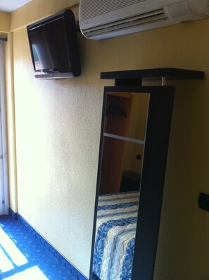 A room with a bed, a mirror, a television, and an air conditioning unit. - Hotel Le Mejean (Lattes)