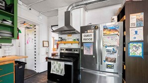 A kitchen with a stove, oven, and a refrigerator labeled "GUEST FRIDGE". - Bunk+Brew Historic Lucas House - Hostel (Bend)