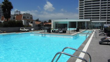 Una piscina al aire libre, sombrillas, sillones reclinables de piscina