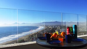 Une table séparée du reste de la pièce par une paroi en verre, donnant sur une plage et offrant une vue sur la ville.