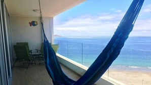 Un fauteuil suspendu sur un balcon avec vue sur l’océan.