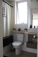 Un baño moderno con inodoro, lavabo y una ventana sobre el lavabo.