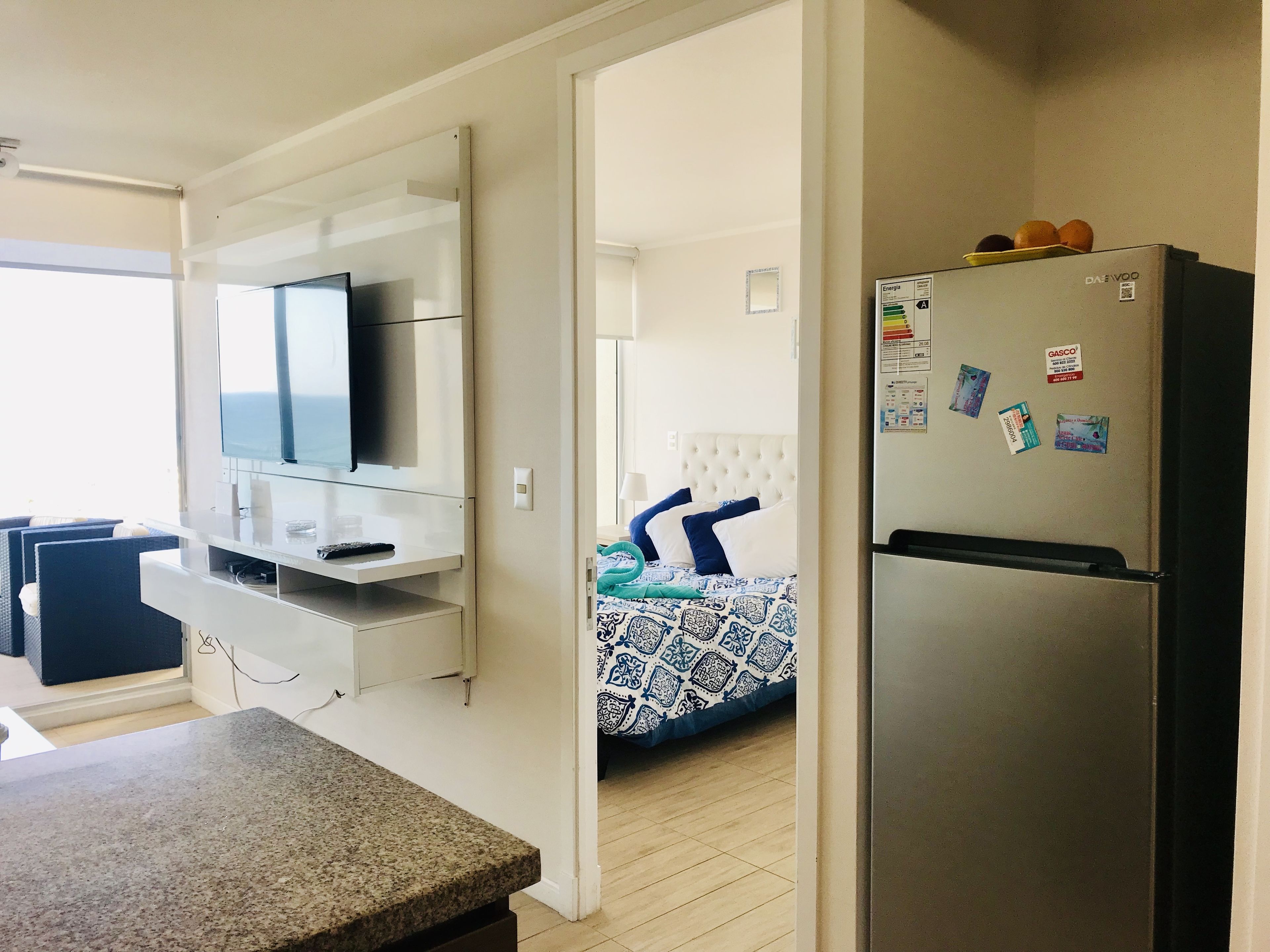 Una cocina moderna con refrigerador empotrado, microondas y televisor de pantalla plana.