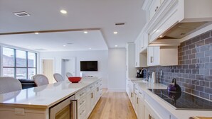 A modern kitchen with a large island, white cabinetry, and a tiled backsplash. - Exclusive Property Just Steps from History & Culture (Charleston)