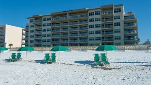 Een strandhotel met meerdere balkons, strandstoelen en parasols.