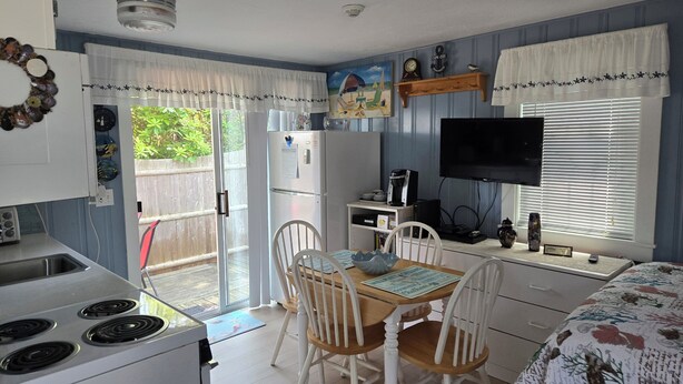 A compact kitchen with a stove, refrigerator, and dining area with chairs and a table. - Cozy studio only 3/10 of a mile from Nantucket Sound, Free WIFI (Dennis)