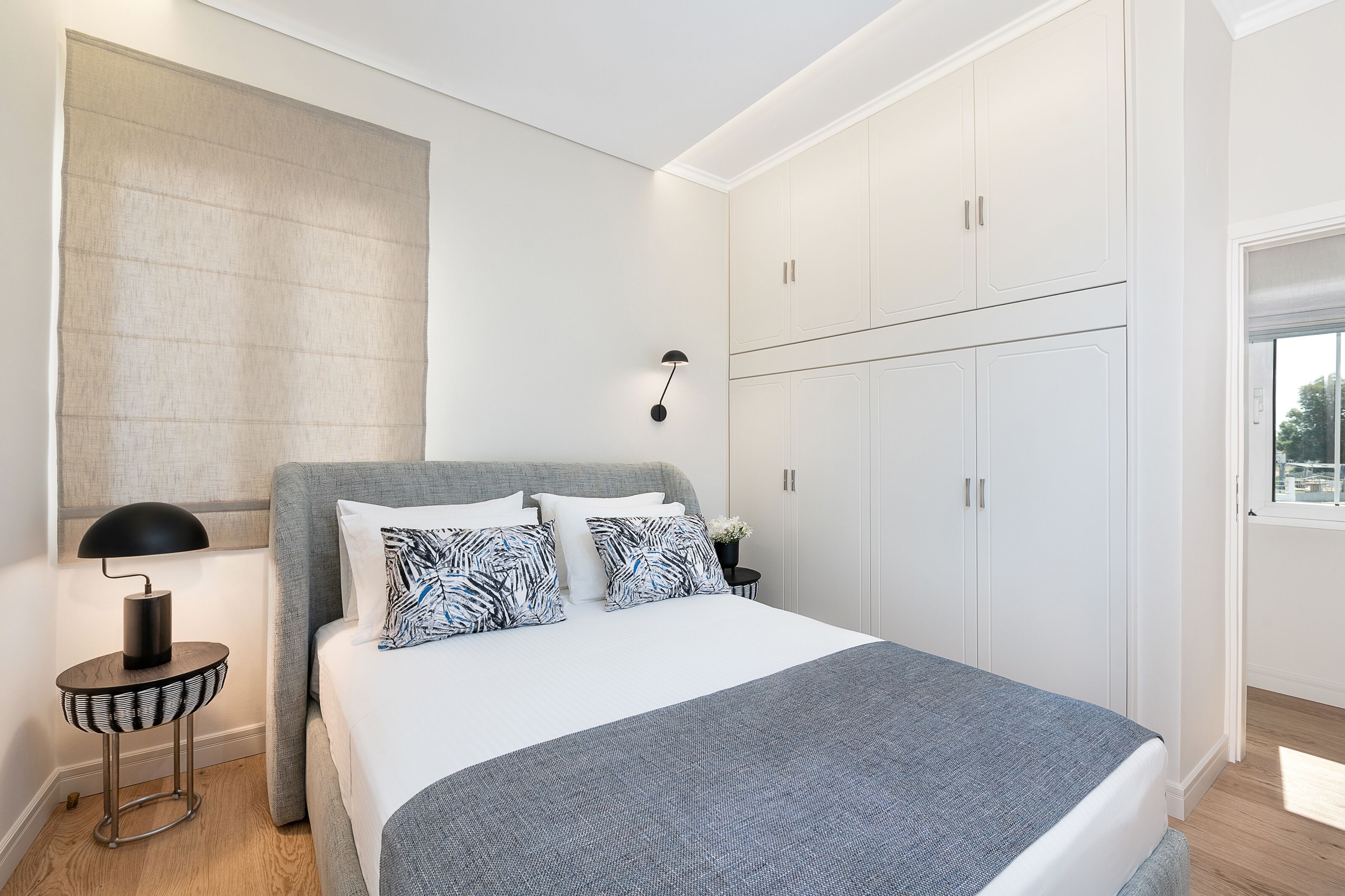 Un dormitorio moderno con una cama grande, un armario blanco y una lámpara de noche.