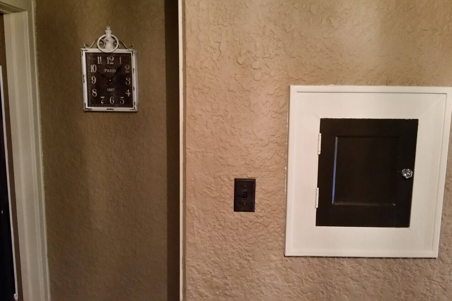A door with a window, a wall clock, and a light switch.