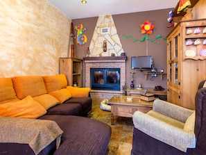 A living room with a fireplace, a sofa, a television, and a cabinet with decorative items.