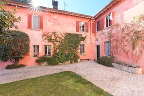 A courtyard with a red building, a tree, and a bench.
